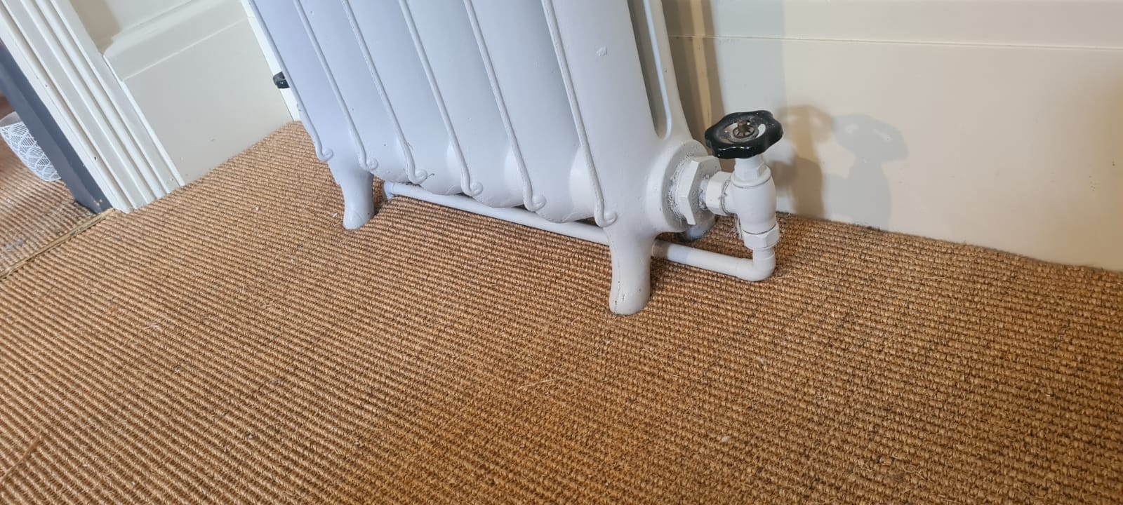 Natural sisal carpet fitted around traditional cast iron radiator, Manchester